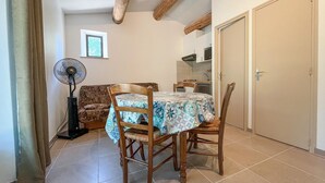 Un coin repas avec une table dressée pour deux personnes, un ventilateur et un canapé.