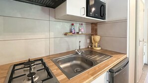 Une cuisine moderne équipée d’un évier en acier inoxydable, d’une cuisinière à gaz et d’un four à micro-ondes.