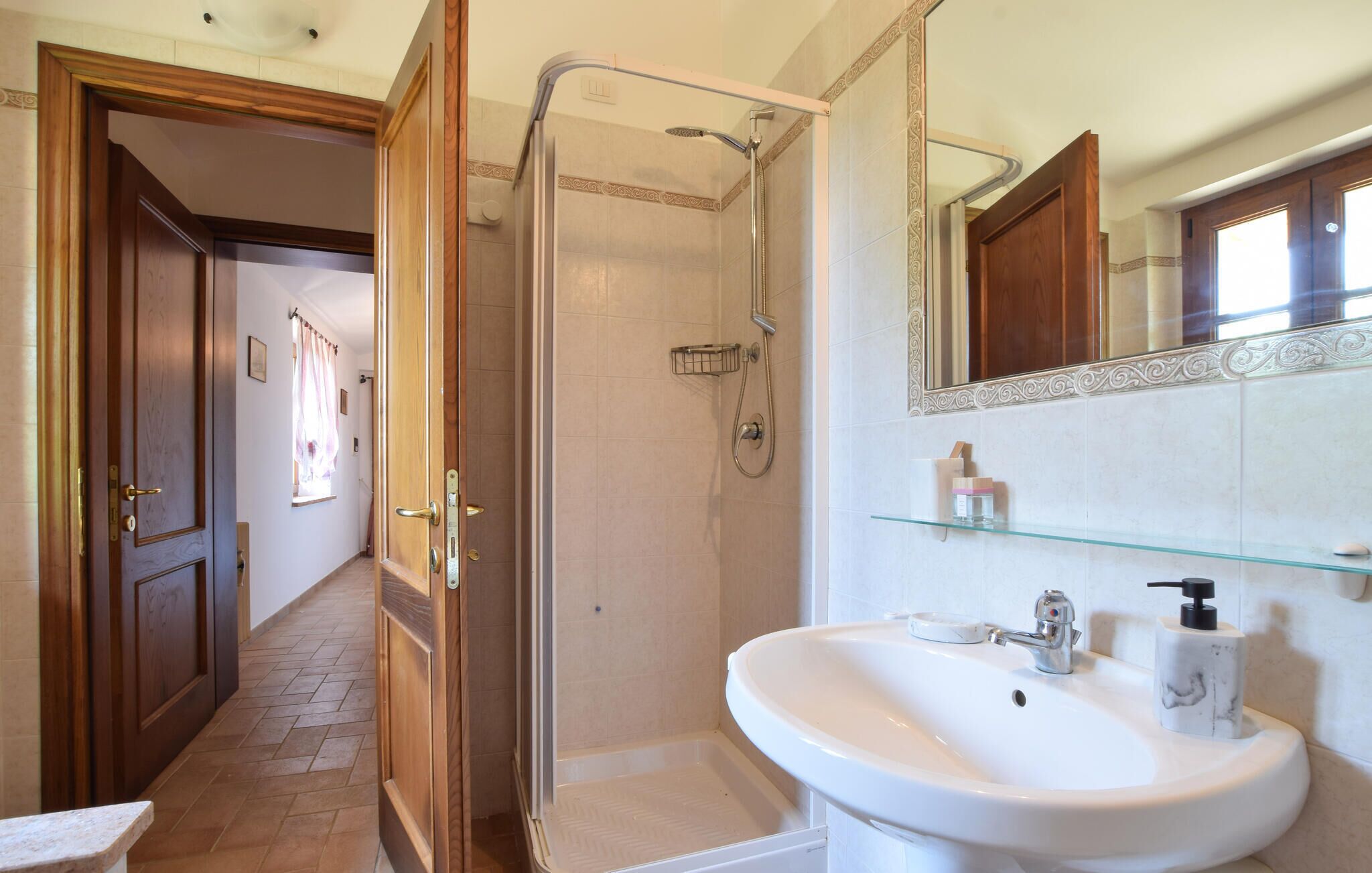 Een badkamer met een douche, wastafel en spiegel.
