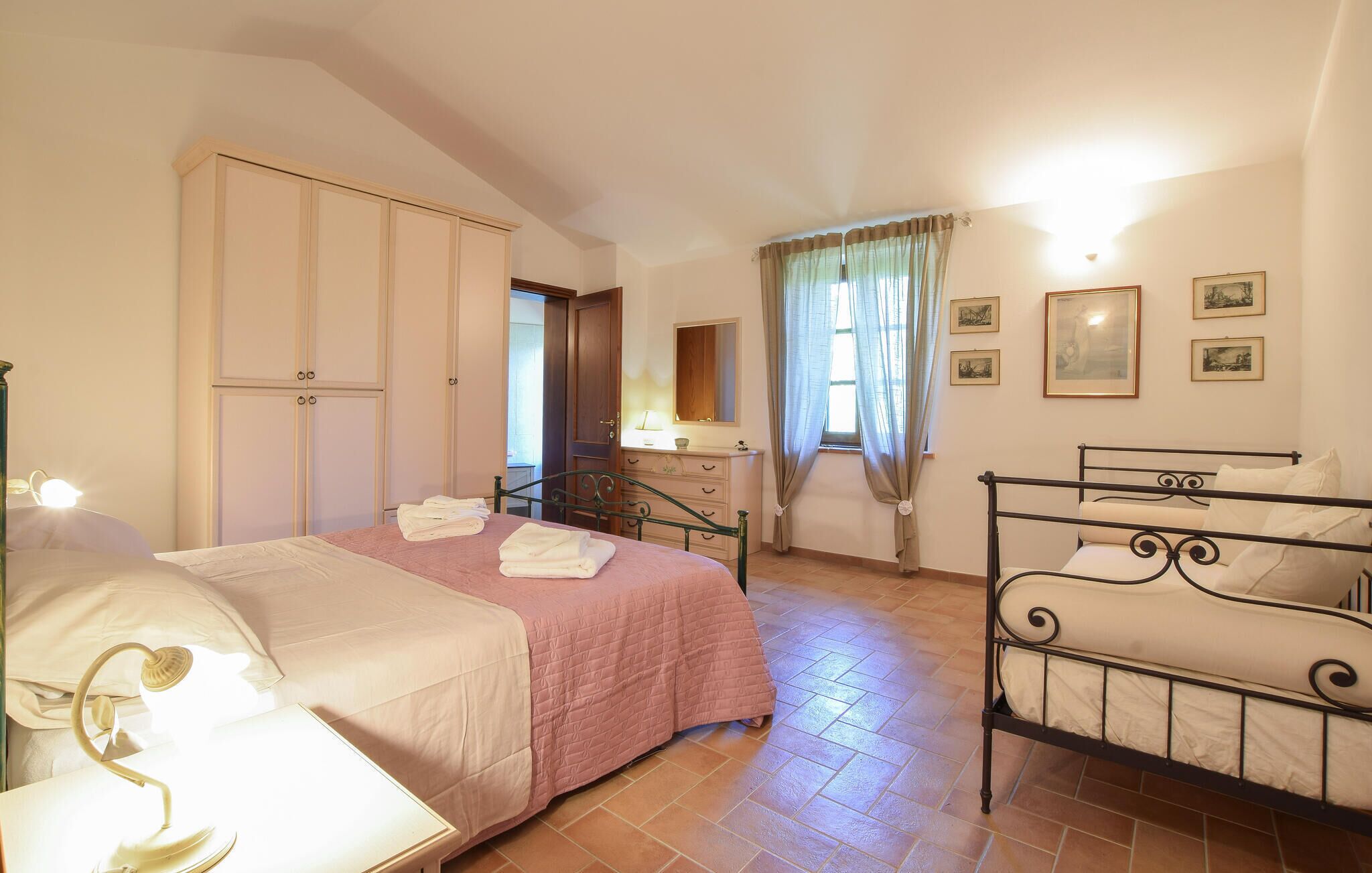 Une chambre à coucher comprenant un lit, une commode, une coiffeuse et une fenêtre avec des rideaux.