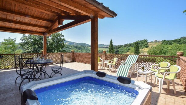 Un jacuzzi en un porche techado con vistas al campo.