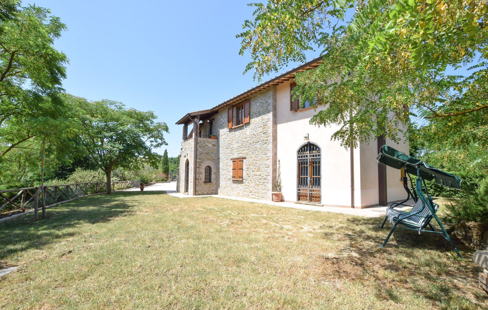 A stone building with a tiled roof, arched windows, and a covered outdoor seating area.