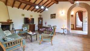 Una sala de estar acogedora con chimenea, muebles de madera, un televisor y un comedor.