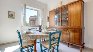 A dining room with a round table, blue chairs, and a wooden cabinet with glass doors. - 2 bedroom amazing apartment in Recco (Recco)