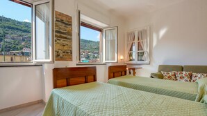 A bedroom with two beds, a view of a hillside town, and a stone wall. - 2 bedroom amazing apartment in Recco (Recco)