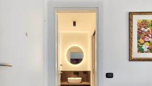 A modern bathroom with a marble floor, a round mirror, and a sink.