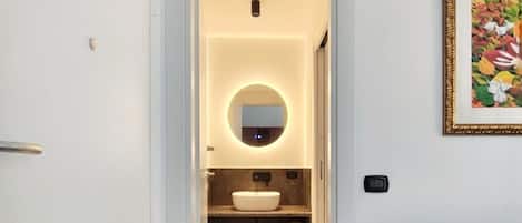 A modern bathroom with a marble floor, a round mirror, and a sink.