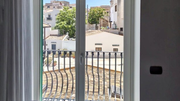 A room with a large sliding glass door leading to a balcony with a metal railing.