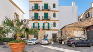Un edificio con diversi balconi, un vaso di grandi dimensioni e auto parcheggiate di fronte.