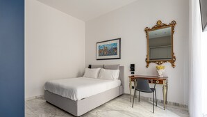 Una camera da letto con un letto, una scrivania, una sedia, uno specchio e un quadro appeso al muro.