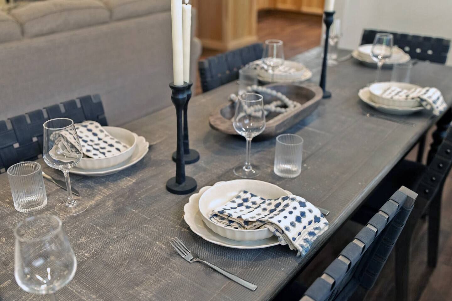 Une table à manger dressée avec des assiettes, des verres et un chandelier.