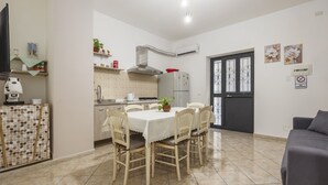 A modern kitchen with a dining table, chairs, and a refrigerator.