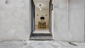A doorway leading to a room with a table and chairs, a ceiling light, and a small sign on the wall.