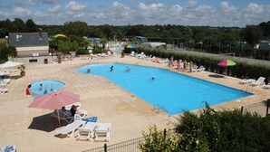 A large outdoor swimming pool with multiple lanes, surrounded by lounge chairs and umbrellas. - SEA VIEW HOUSE FACING GLENANSR ISLANDS (LA FORET-FOUESNANT)