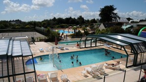 A swimming pool area with multiple pools, sun loungers, and a covered seating area. - SEA VIEW HOUSE FACING GLENANSR ISLANDS (LA FORET-FOUESNANT)