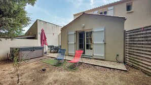 A small house with a patio, a sliding glass door, and a wooden fence. - Beautiful home in Jard-Sur-Mer with WiFi (Jard-Sur-Mer)