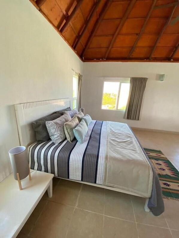 Une chambre à coucher avec un lit, une table de chevet, une fenêtre et une vue sur l’extérieur.