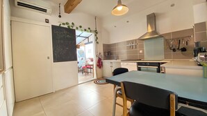 Une cuisine moderne dotée d’un grand îlot central, d’appareils électroménagers en acier inoxydable et donnant sur la salle à manger.