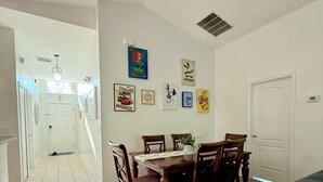 Un comedor con una mesa y sillas de madera, una puerta blanca y varias fotos enmarcadas en la pared.