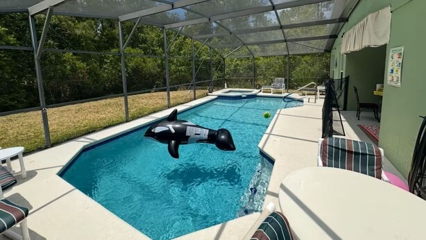 Zona de piscina interior con techo, tabla de clavados y sillas de descanso.