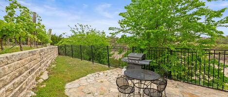 An outdoor patio with stone flooring, a round table, and metal chairs.