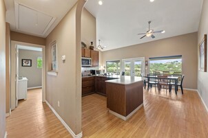 Una cocina amplia con armarios de madera, una isla central y un comedor con vistas al exterior.