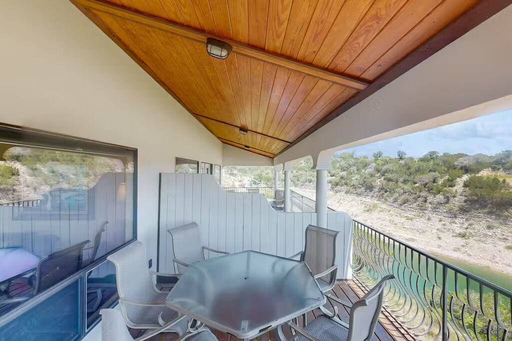 Un espacio de estar techado al aire libre con una mesa y sillas, con vistas a un paisaje natural.