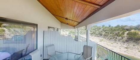 Un espacio de estar techado al aire libre con una mesa y sillas, con vistas a un paisaje natural.