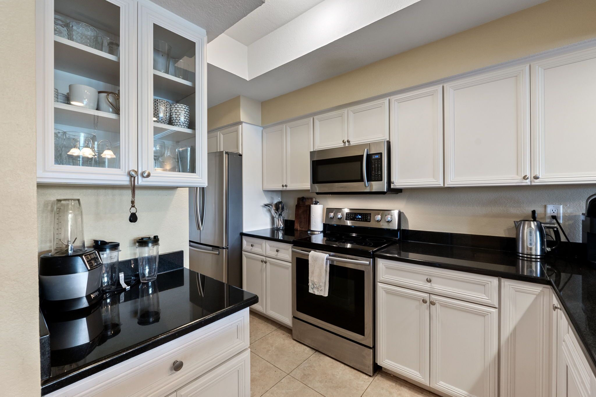 A modern kitchen with white cabinetry, stainless steel appliances, and black countertops.