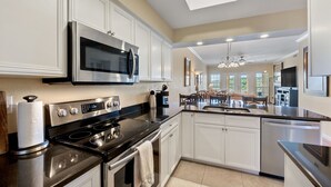 Una cocina moderna con electrodomésticos de acero inoxidable, armarios blancos y una isla central.