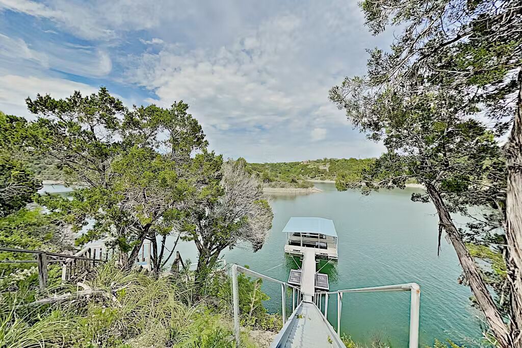 A dock extending into a calm lake surrounded by trees.