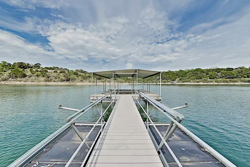 A boat dock with a covered area and a view of a calm lake and distant shoreline.