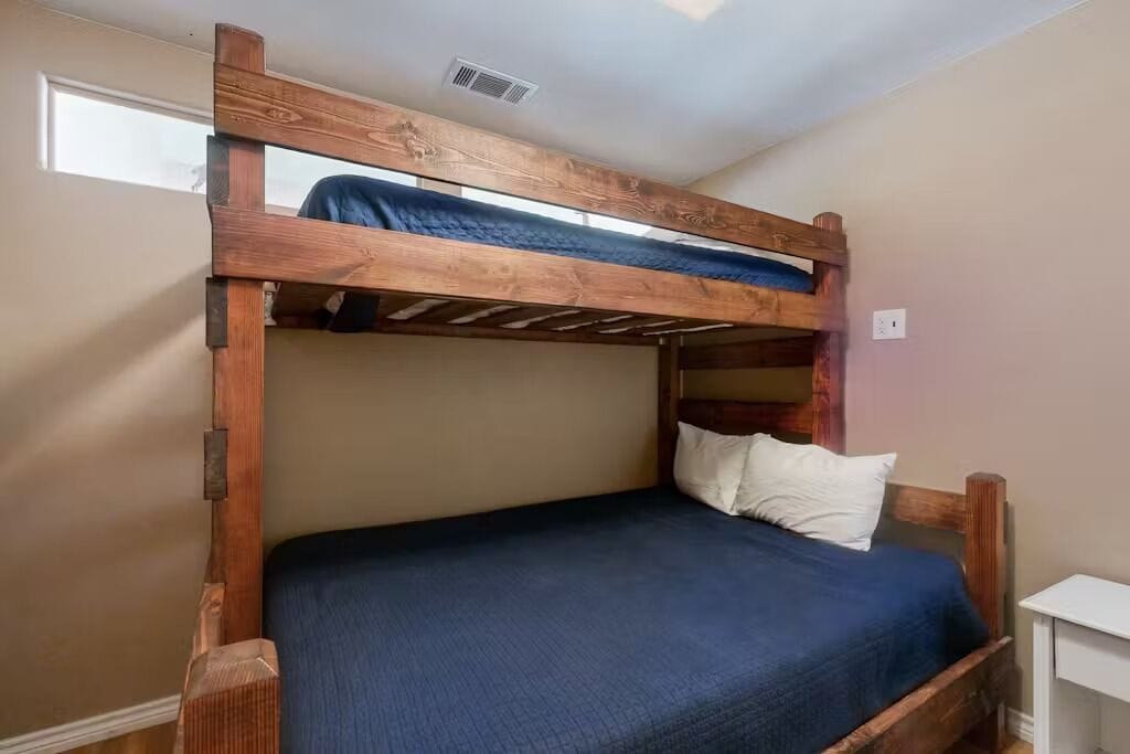 A bunk bed with a wooden frame, a blue mattress, and white pillows.