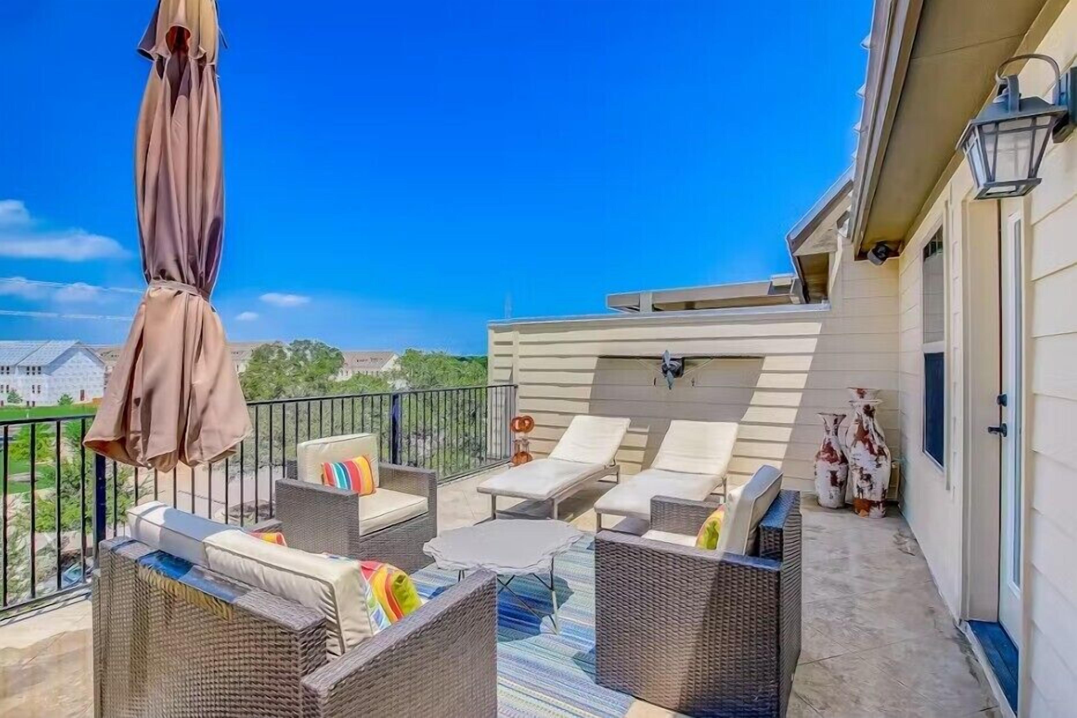 A balcony with wicker furniture, a table, and two chairs.