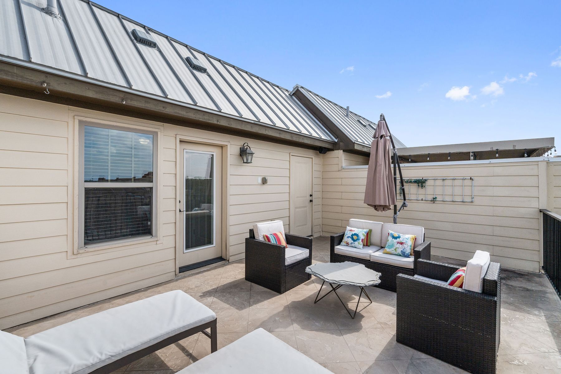 A patio area with outdoor furniture, a door, and a metal roof.