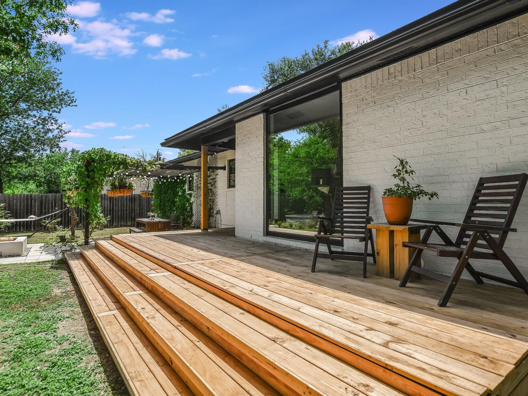 A wooden deck with outdoor seating and a white brick wall.