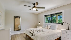 A bedroom with a bed, nightstands, a ceiling fan, a window with a view, and a mirror. - Charming Ranch Home Near Dell With Cocktail Pool (Round Rock)