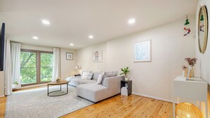 Un salón moderno con un sofá gris, una mesa de centro y un ventanal con cortinas.