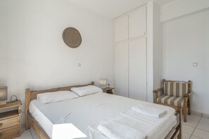 Une chambre à coucher avec un lit en bois, une table de chevet, une chaise et une armoire.