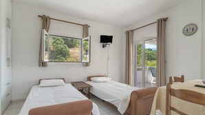 A hotel room with two beds, a TV, a table, and a view of the outdoors. - Apartment '1 Bedroom  with Balcony 5' with Sea View, Wi-Fi and Air Conditioning (Spartià)