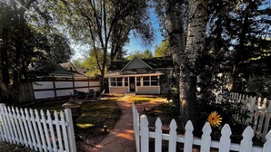 A residential property with a paved pathway leading to a house, surrounded by a white picket fence and mature trees. - Charming, Updated Old Town Fort Collins home in a Super location... (Fort Collins)