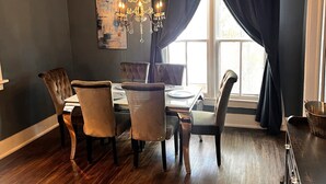 A dining room with a dark wood floor, a chandelier, and a large window with dark curtains. - Charming, Updated Old Town Fort Collins home in a Super location... (Fort Collins)