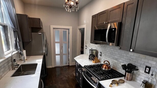 A modern kitchen with dark wood cabinets, a stainless steel refrigerator, a gas stove, and a microwave. - Charming, Updated Old Town Fort Collins home in a Super location... (Fort Collins)