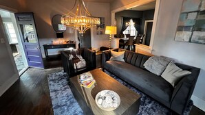 A modern living room with a dark grey sofa, a wooden coffee table, and a chandelier. - Charming, Updated Old Town Fort Collins home in a Super location... (Fort Collins)