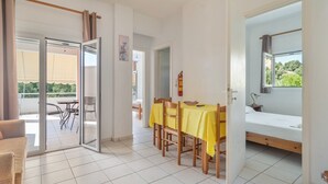 Une pièce comprenant un lit, une table à manger avec des chaises, une porte-fenêtre coulissante donnant sur un espace extérieur et une petite fenêtre avec vue.