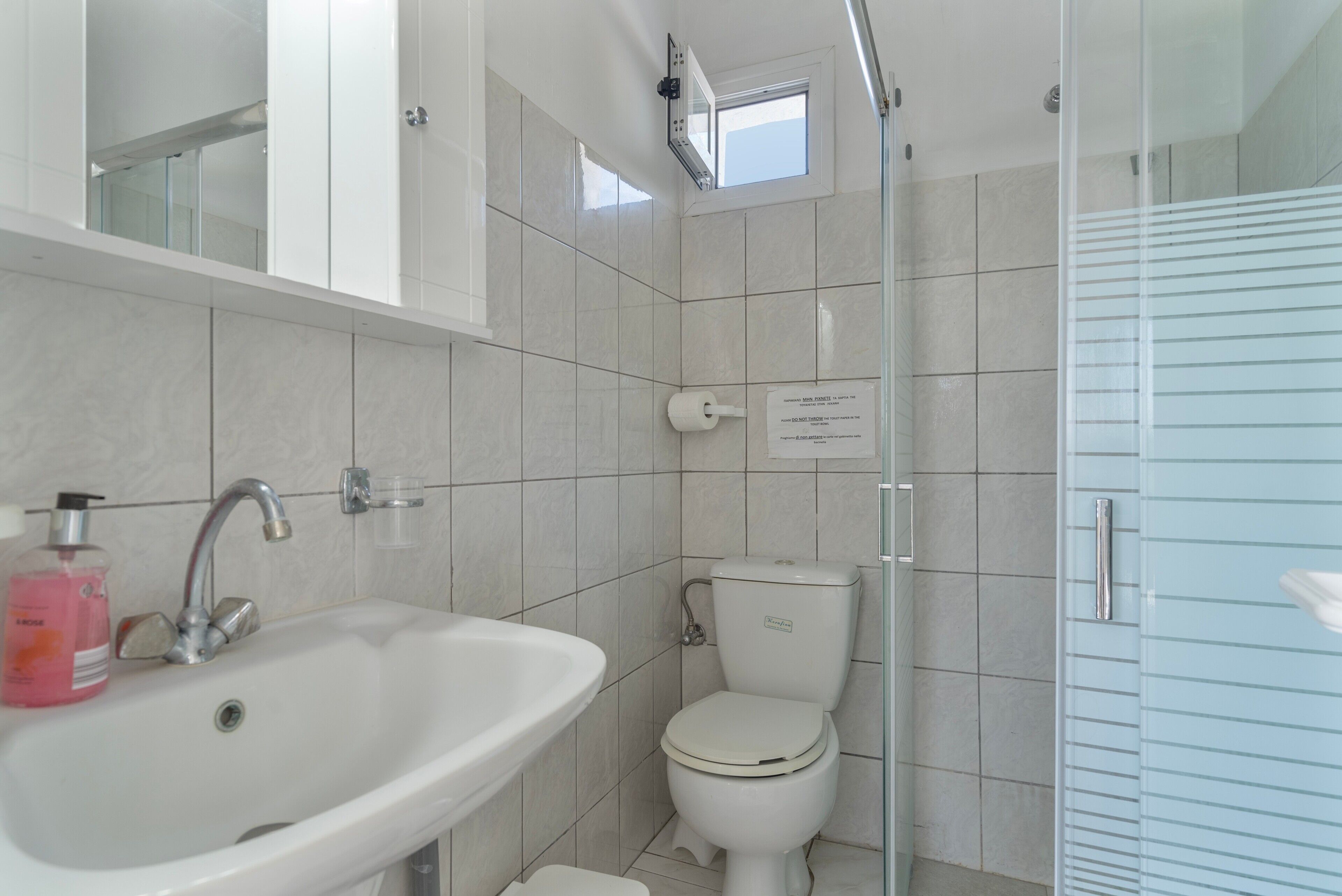A bathroom with a white sink, toilet, and shower.