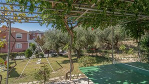 A garden with a swing set, a green table, and a pergola.