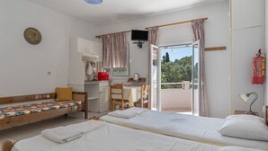 A room with two beds, a desk, a chair, a television, and a balcony with a fire extinguisher.