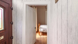 A hallway leading to a bedroom with a wooden floor and a bed. - Tig Davy (Mullagh)