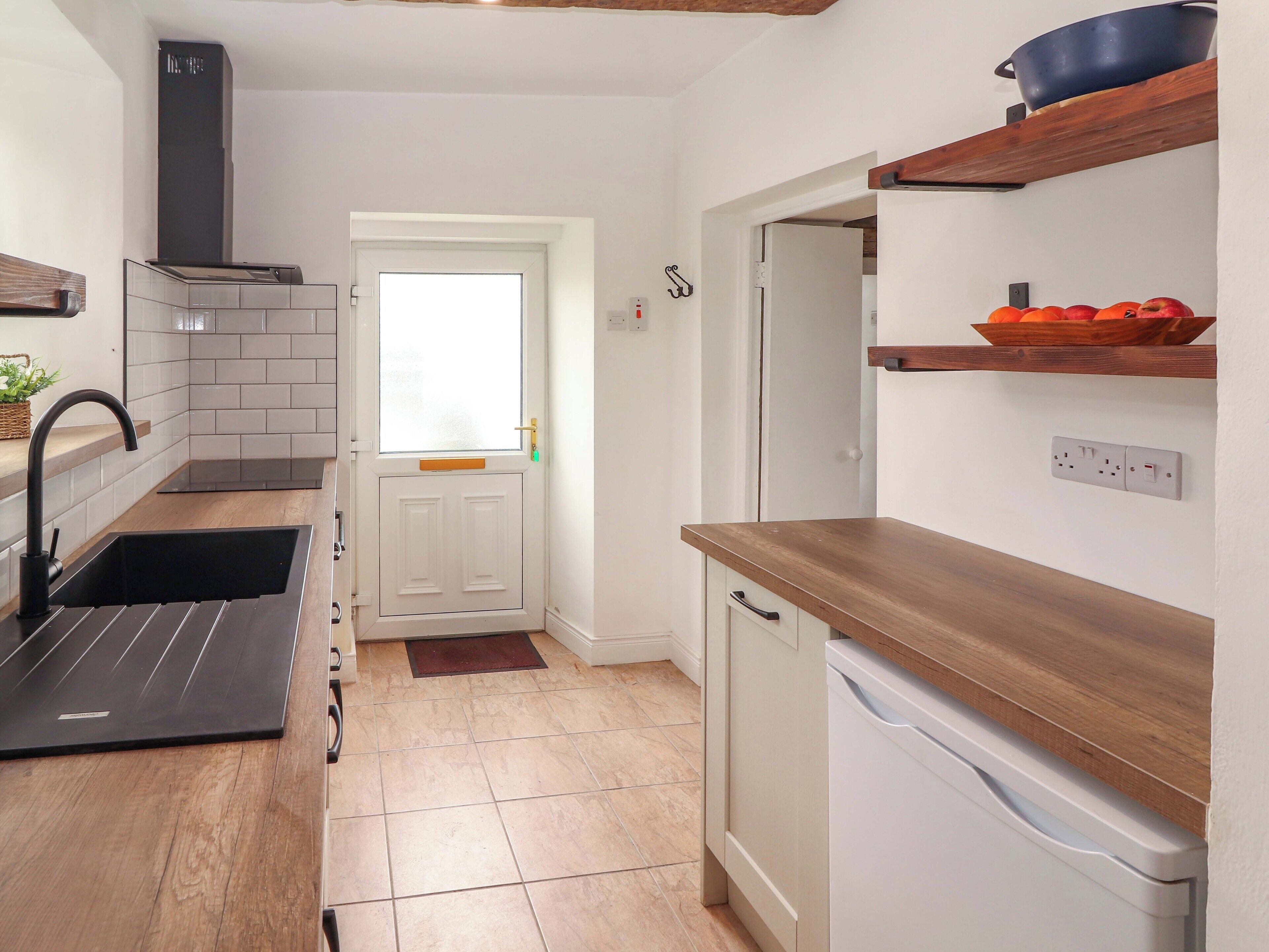 A kitchen with a black sink, a white dishwasher, and a wooden countertop.